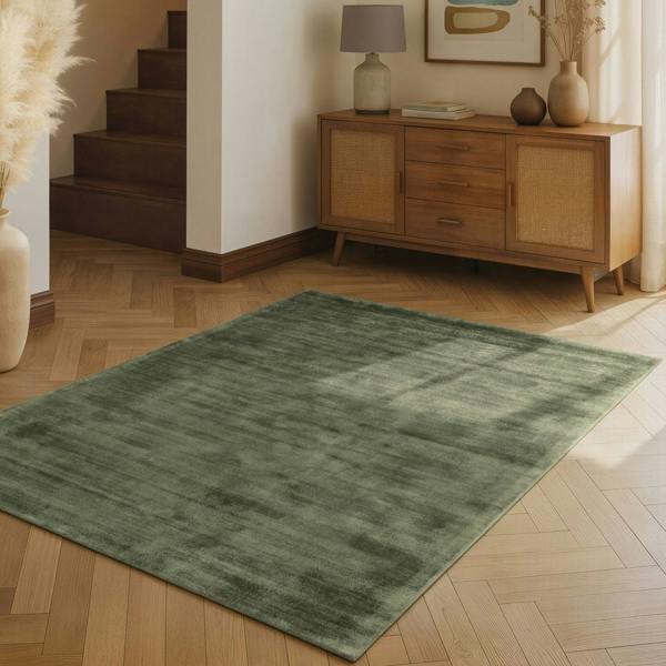 Green rug on a wooden floor with a wooden sideboard and decorative items in the background.