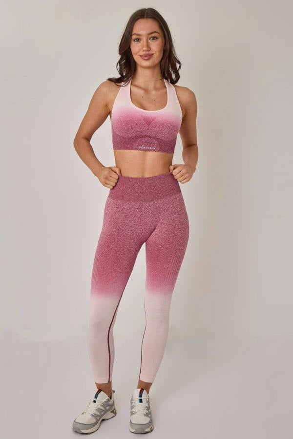Woman wearing a pink and white gradient sports outfit on a plain background