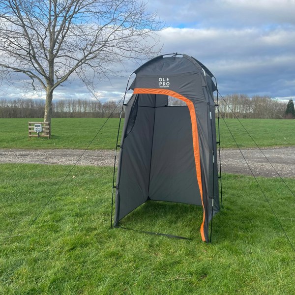 The fibreglass toilet tent from OLPRO pictured in a field of a campsite.