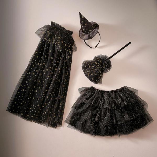 Overhead studio flat lay of the complete black and gold star witch dress-up costume set, including tulle cape, tiered tutu skirt, wand, and hat headband.