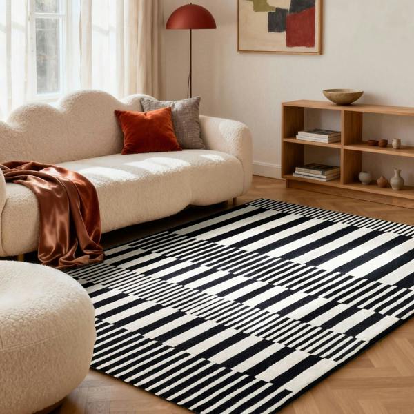 Living room with a black and white striped rug, beige sofa, and wooden shelf.