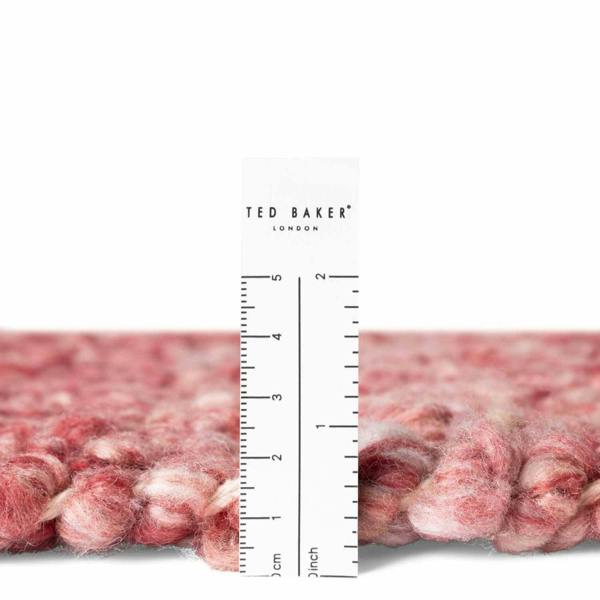 Close-up of a textured pink fabric with a ruler and 'Ted Baker London' branding.