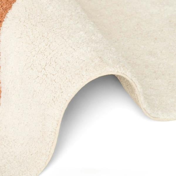 Close-up of a textured beige rug corner on a light gray background