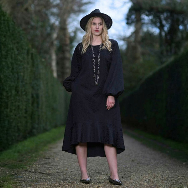 Women's Aphrodite Black Leopard Jacquard Dress, styled with a silver chain necklace and black hat for a chic, coordinated look.