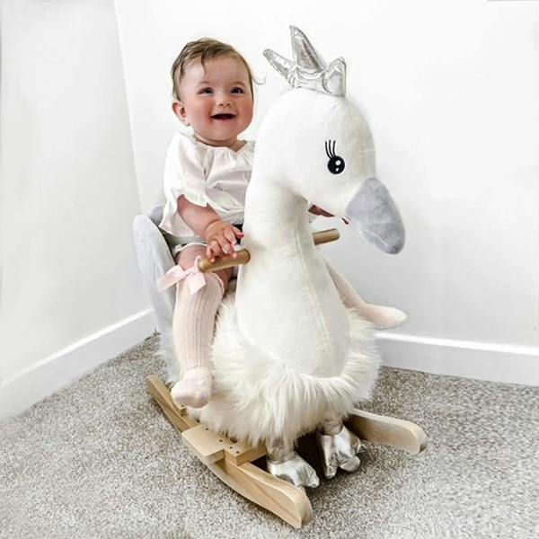 Toddler seated on plush white swan rocking toy with grey seat and wooden rockers