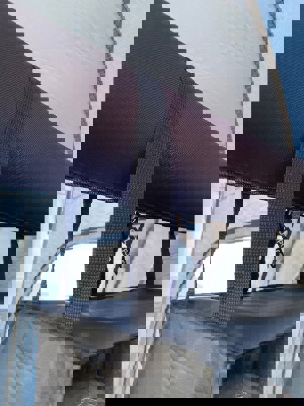 A closeup of the hanging straps of the Camping Organiser with Shelves and Storage bag which are hanging on a storm bar of a campervan awning.