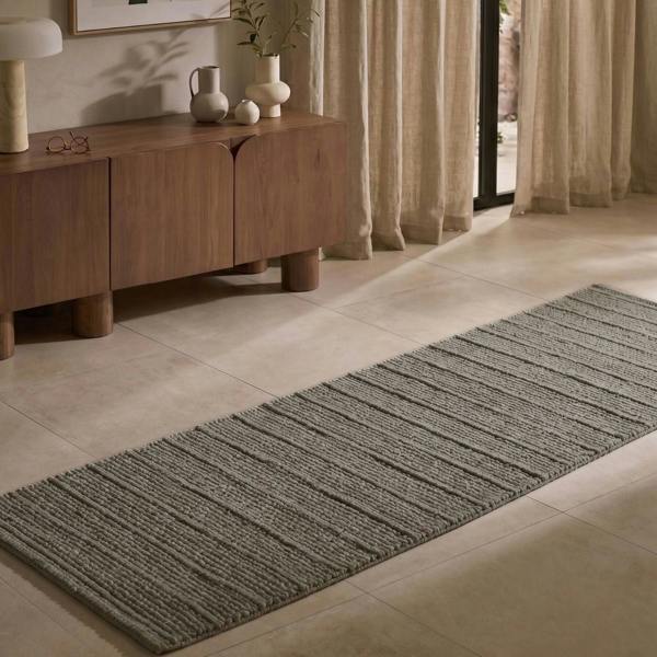 Gray runner rug on a tiled floor in a room with wooden furniture and curtains.