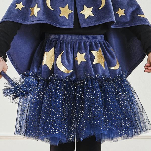 Close-up of a child wearing a navy velvet wizard tutu skirt with gold foil moons and stars over sparkly blue tulle.