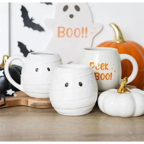 White ceramic mummy-shaped oil burner with black dot eyes on a tabletop display