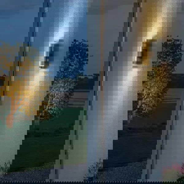 brass up down outdoor wall light mounted on a white textured wall outside a house