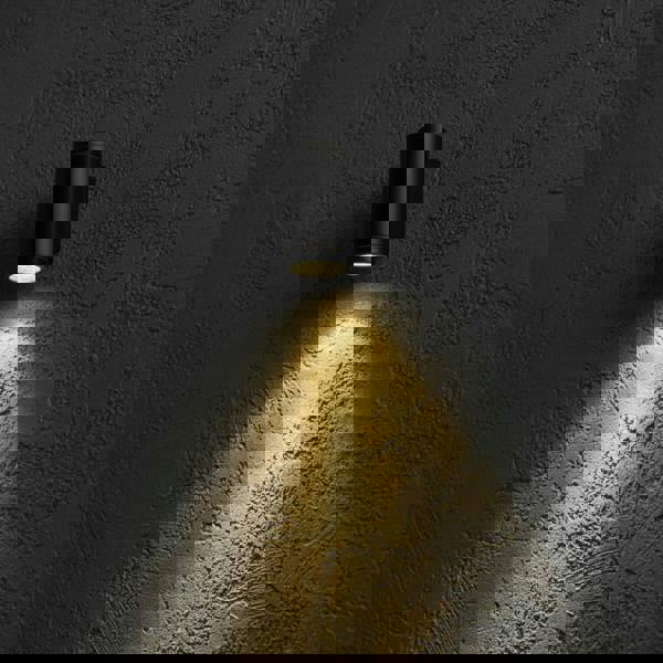 black outdoor LED wall downlight mounted on a textured exterior wall 