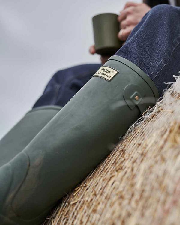 Farmer wearing Braemar wellies sitting on hay bale perfect for yard chores and comfort breaks