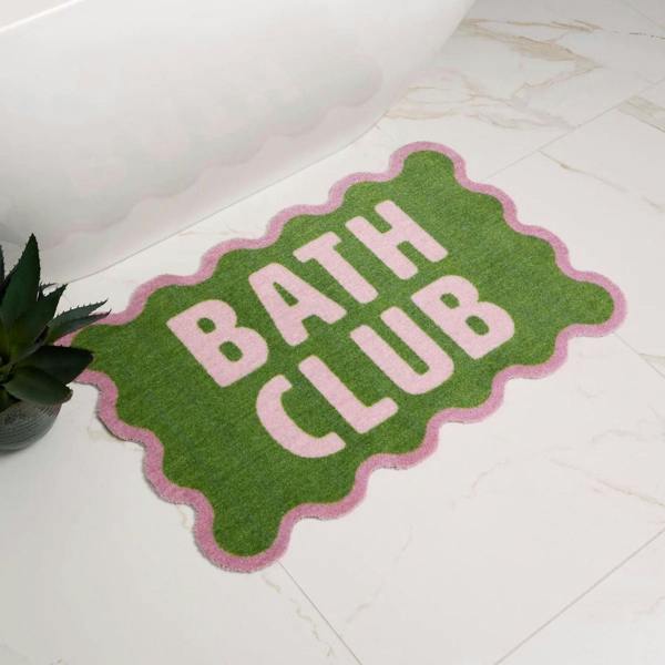 Green bath mat with 'Bath Club' text on a tiled bathroom floor.