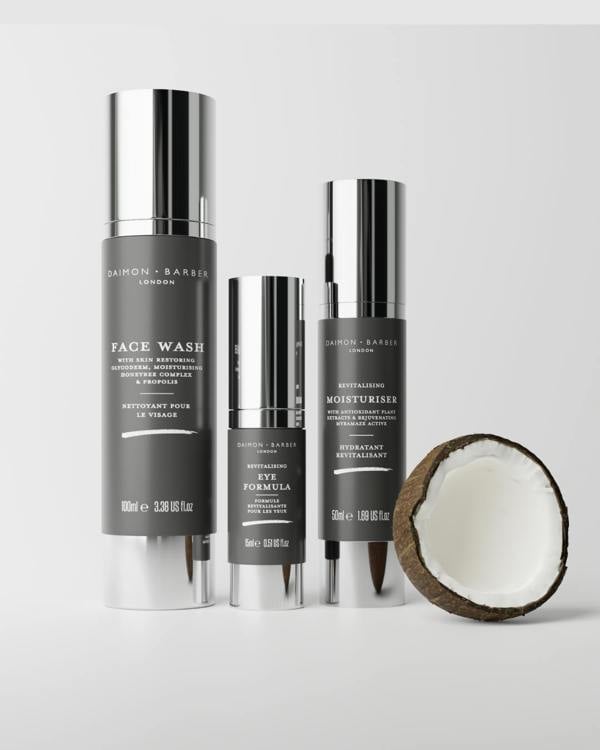 Daimon Barber Face Wash, Eye Formula and Moisturiser bottles with a coconut half on a light gray background