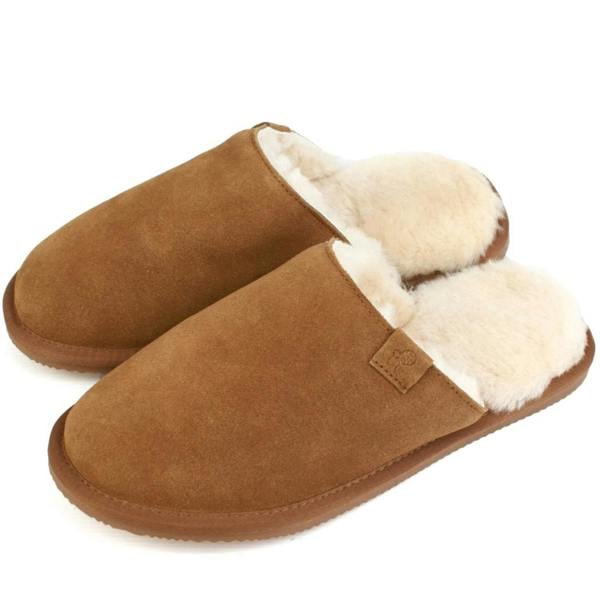A pair of men's slip-on slipper mules showing the rich chestnut tan suede exterior, a thick trim of natural cream sheepskin wool at the opening, and a subtle matching tan pull-tab on a white background.