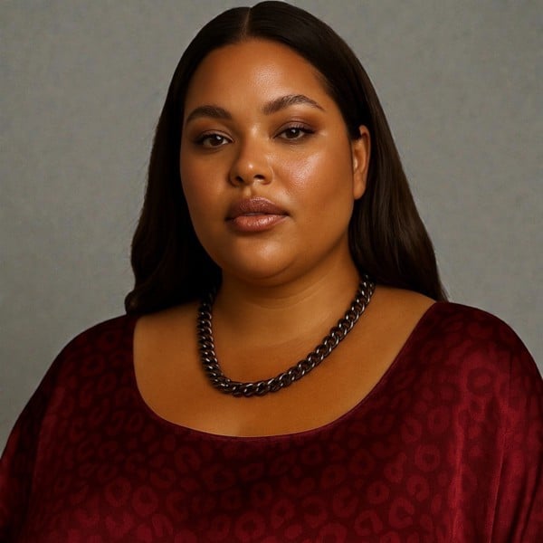 Woman wearing a burgundy dress and a single chain black aluminium and metal chain necklace a against a plain background