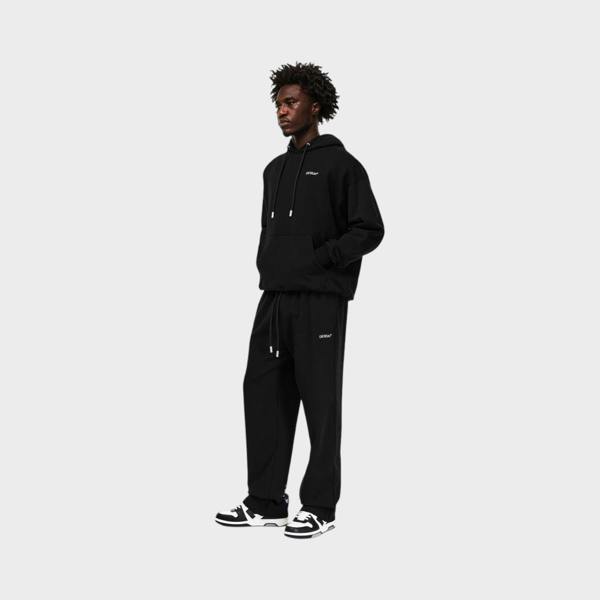 Supplied Fashion model wearing black heavyweight fleece sweatpants with signature arrow branding and closed hems
