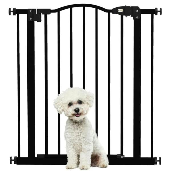 Black pet gate with vertical bars, small white dog sitting behind the barrier