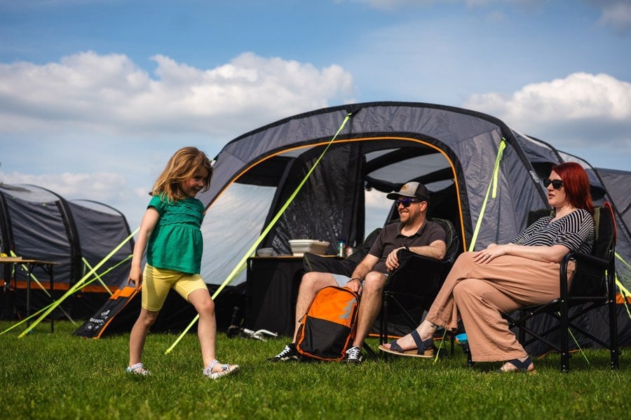 A family sit outside the Discovery 6 Berth Inflatable Tent on a campsite