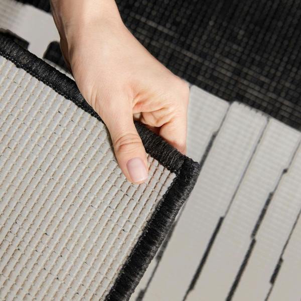 Hand holding a corner of a gray and black textured mat