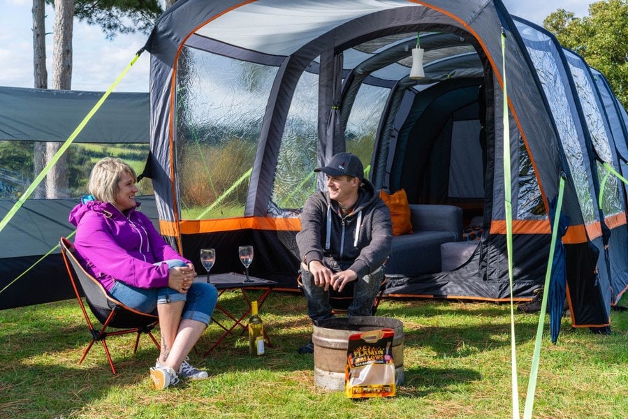 A male and female sat outside Blakedown Breeze 4 Berth Inflatable Tent from OLPRO on a campsite.