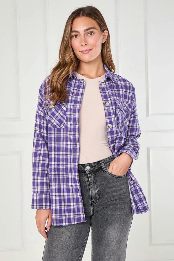 Woman wearing a purple plaid shirt over a beige top and gray jeans against a white background
