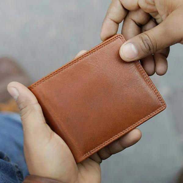 Person holding men’s genuine brown leather bifold wallet