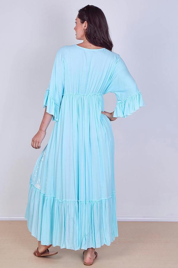 Woman wearing a light blue dress with ruffled sleeves against a white background