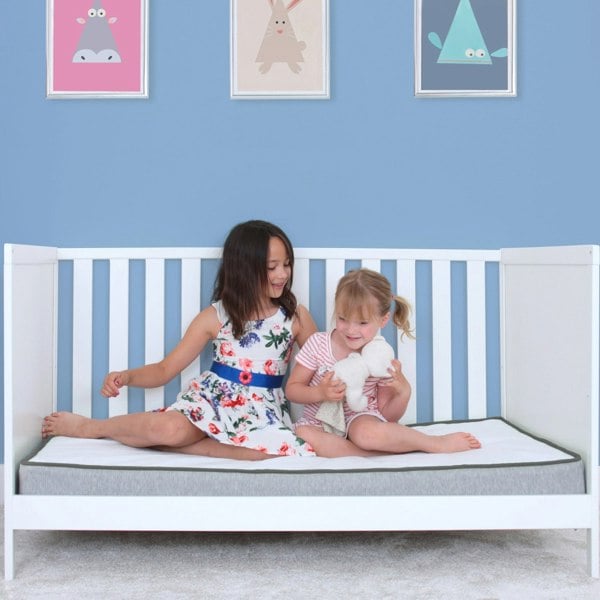 Girls sitting on the mattress in a cot bed