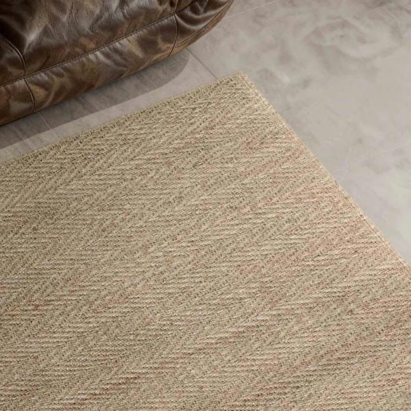 Beige textured rug on a tiled floor with a brown leather chair corner.
