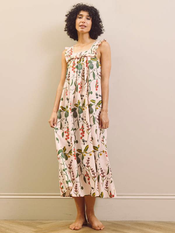 Woman wearing a floral & Pear night dress against a plain background