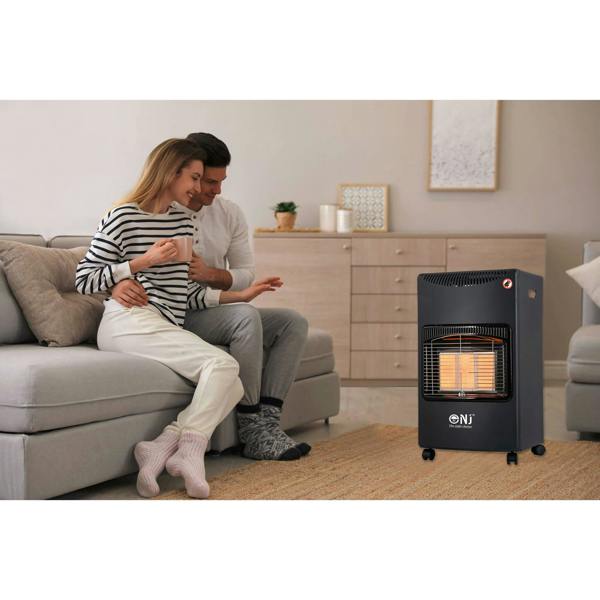 Couple sitting on a couch next to a portable heater in a living room.