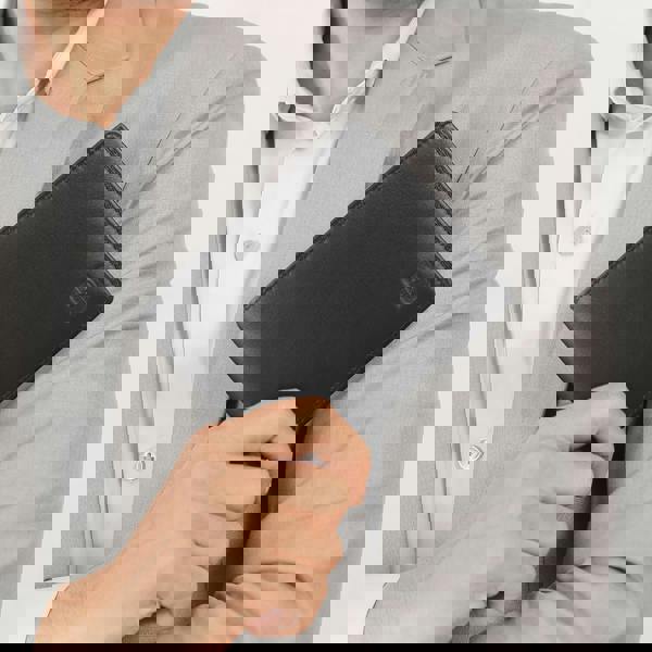 Person holding a black wallet with a visible brand logo against a neutral background