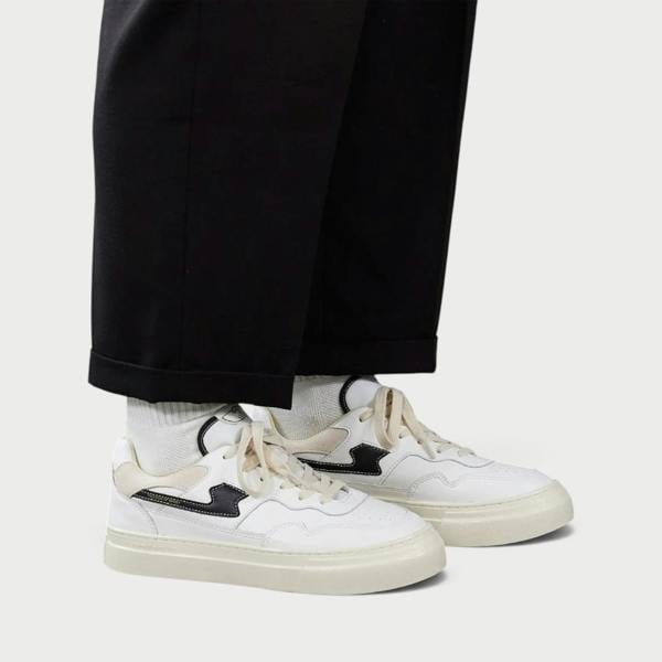 Supplied Fashion Pearl S-Strike white and black leather sneakers worn with white socks and black trousers