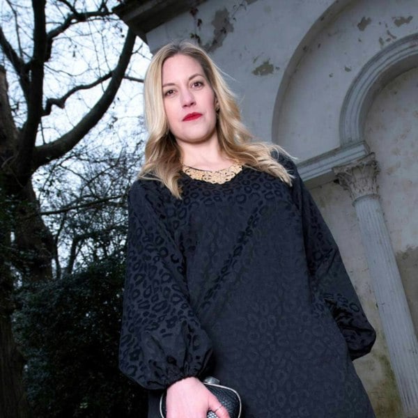 Women's Aphrodite Black Leopard Jacquard Dress shown as a close up, styled with a gold necklace and black gold clutch for a chic, coordinated look.