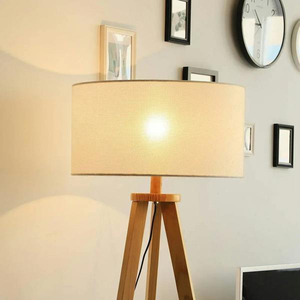 Cream fabric drum shade on a natural wood tripod floor lamp with warm light