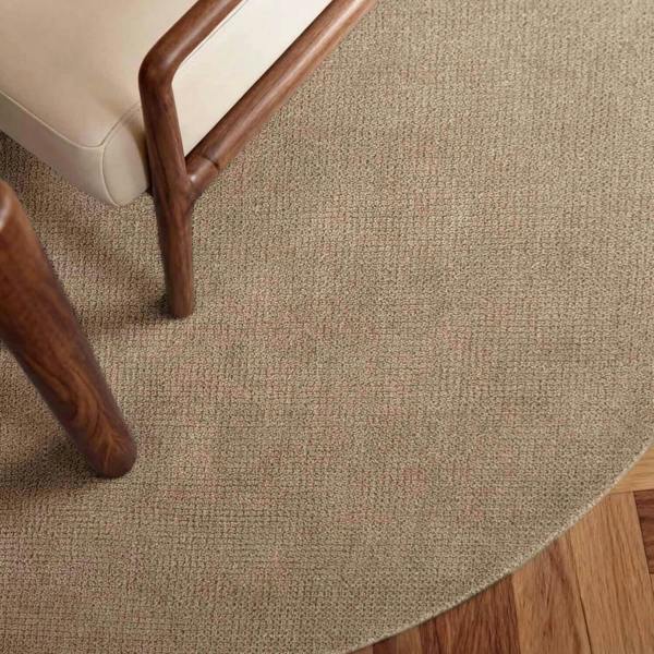 Close-up of a textured beige carpet with wooden furniture legs.