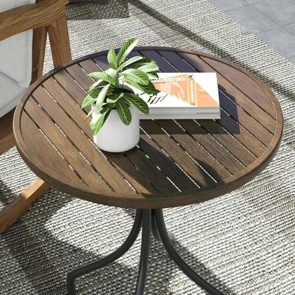 Close-up of round brown slatted tabletop with potted plant on black pedestal legs.