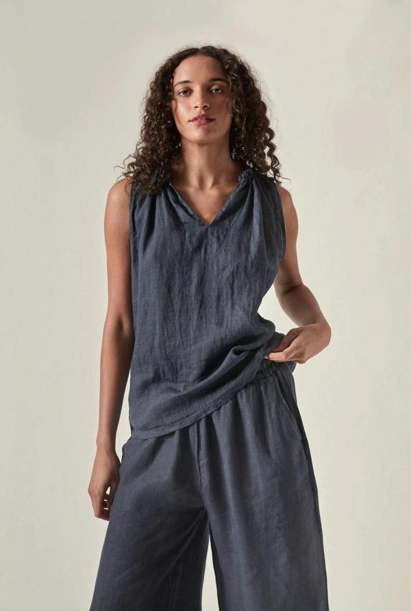Woman wearing a navy sleeveless top by james Lakeland and pants against a soft beige background