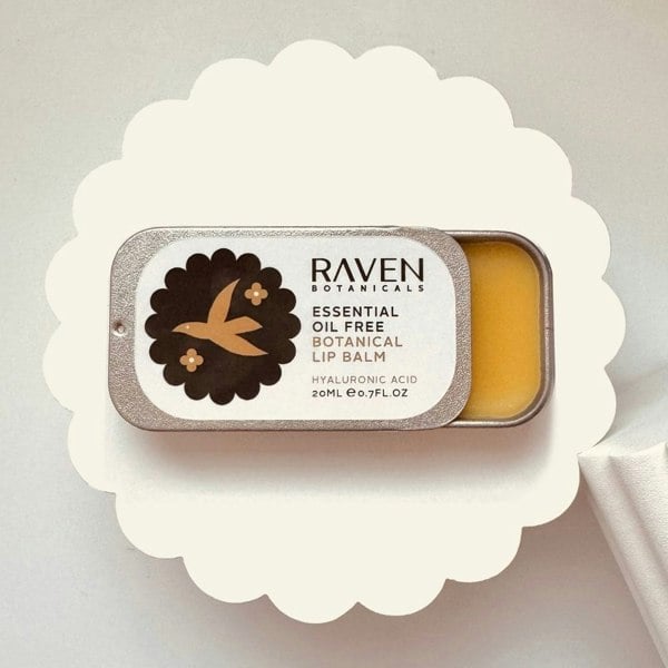 Essential Oil Free natural Lip Balm by Scottish Skincare brand Raven Botanicals, displayed open on a white riser in a plastic free sliding lid tin