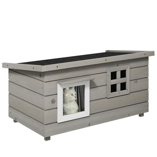 Grey wooden elevated outdoor cat house with asphalt roof, front windows, and open doorway