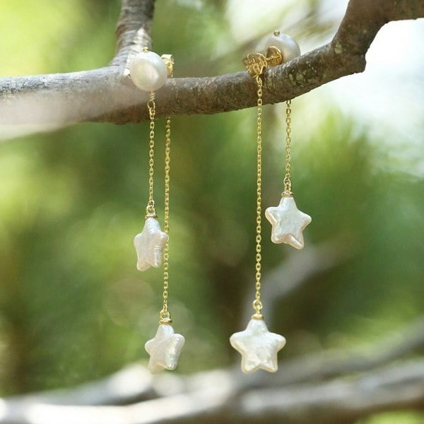 Gold vermeil star pearl drop earrings hanging off a tree branch.