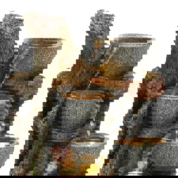 Rustic electric water feature with three textured stone bowls cascading water, surrounded by a natural wood-like base and earthy colors