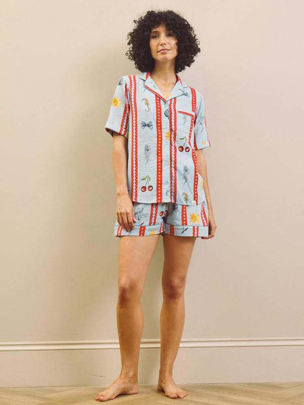 Woman wearing a patterned short pyjama set against a beige wall.