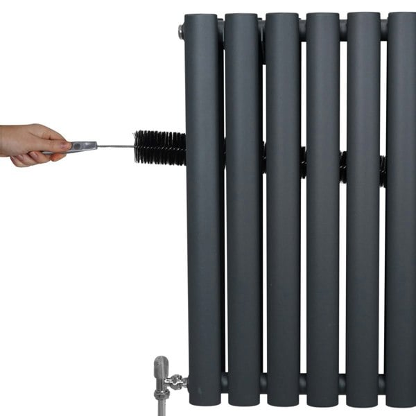 Anthracite grey oval column radiator with sleek vertical bars, showing a hand adjusting the valve for optimal heating control