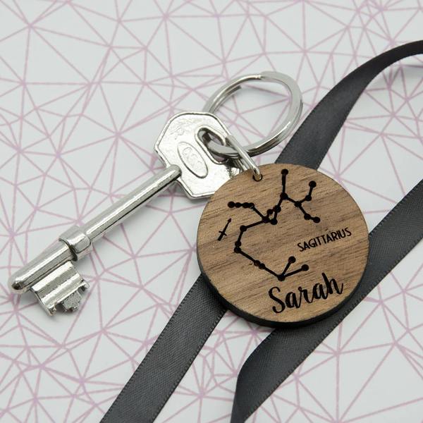 Personalised round walnut wooden zodiac keyring engraved with Sagittarius star sign constellation and the name Sarah.