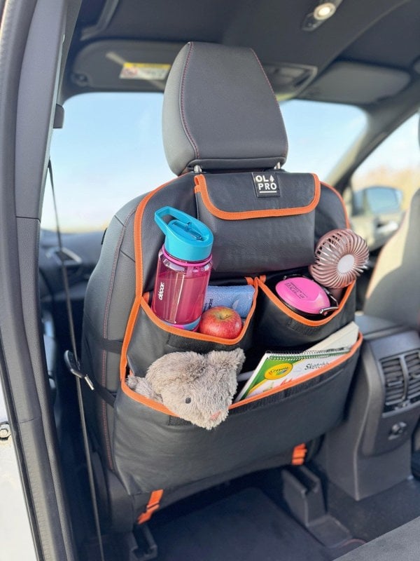 The Rear Single Seat Storage Organiser in Orange by OLPRO attached to the front drivers seat of a VW vehicle full of items for children.