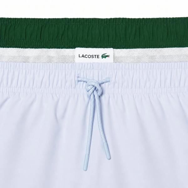 Lacoste light blue quick-dry swim shorts with green waistband and drawstring.
