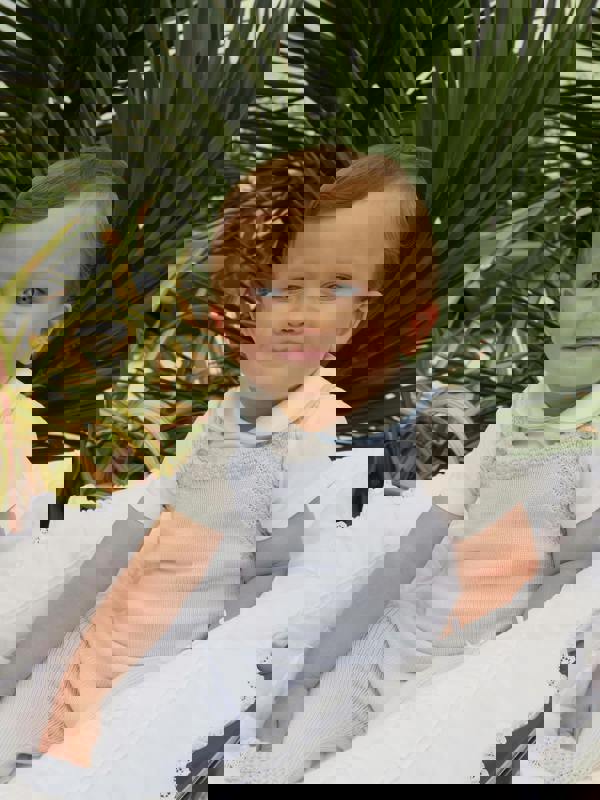 Baby boy wearing blue piping peter pan collar body styled with blue moss stitch strap romper.