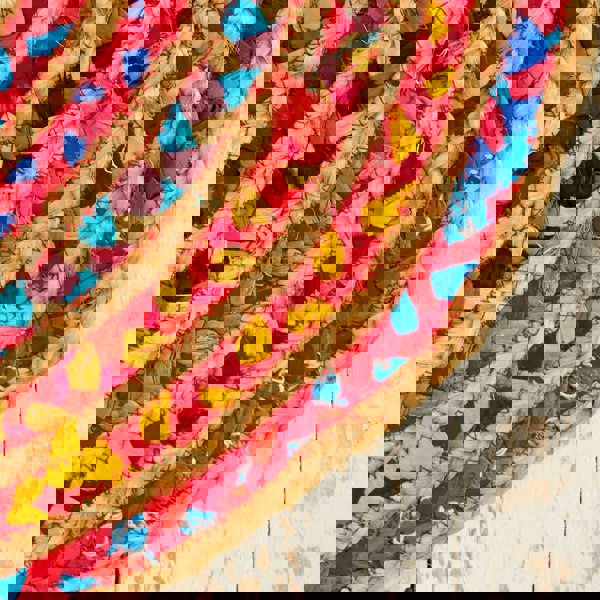 A Multicoloured Jute and Cotton Oval Rag Rug on a wooden surface.